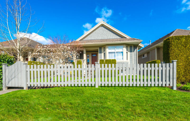 Home with long country style wooden fence with perfectly manicured lawn