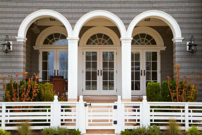 gray home with white trim, french style entrance, and deco style fence