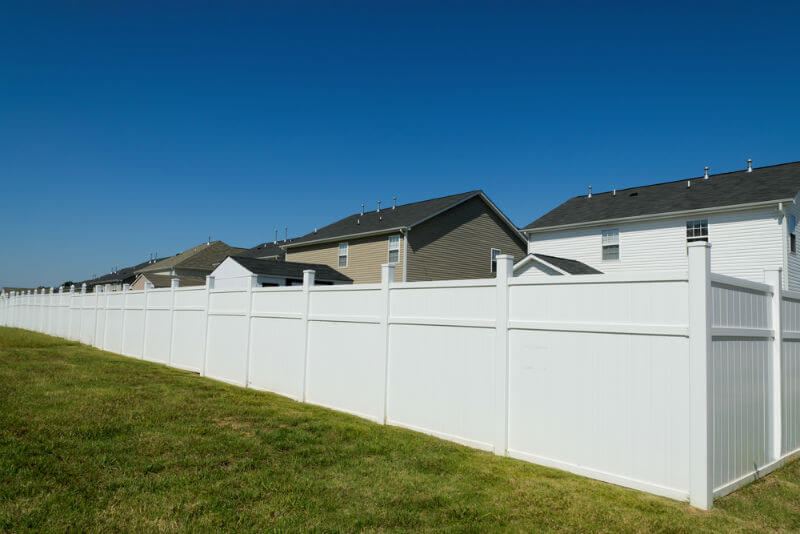 Suburban homes with a long vinyl private security fence