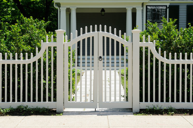 white picket fencing and front gate lead to an elegant home entrance