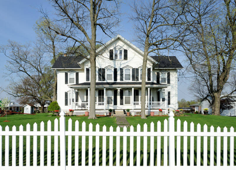 large white house with black shutters and white scallop picket fence